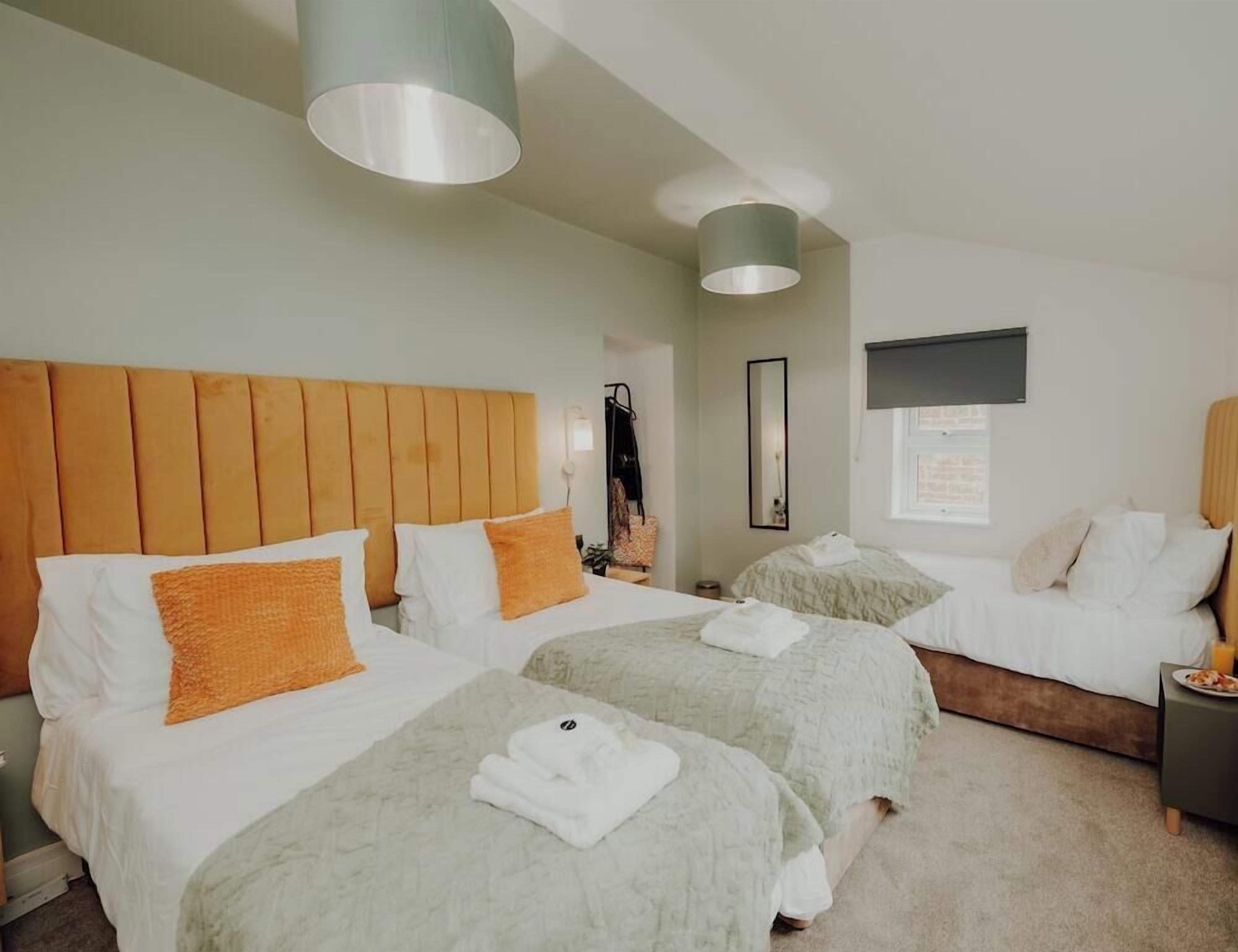 Quarto de hotel com duas camas, cabeceira de madeira e uma janela grande.