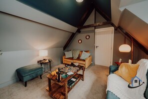 A cozy loft bedroom with a sloped ceiling, a wooden coffee table, a sofa, and a bench. - Penthouse - 5 bed 4 bath sleeps 10 parking wi-fi (Desborough)