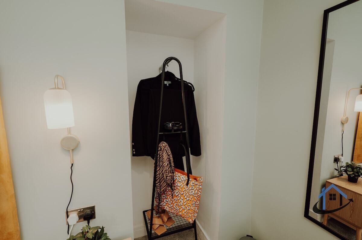 Une pièce comprenant un porte-manteau, un sac suspendu, une lampe et un miroir.