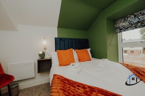A hotel room with a bed, a nightstand, a lamp, a red chair, and a window with a view. - Apt 3 - 2 Bed 2 bath sleeps 5 free parking wifi (Desborough)