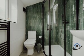 Ein Badezimmer mit Toilette, Mülleimer und Duschbereich mit Glastür.
