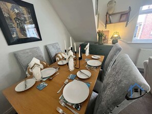 A dining area with a wooden table set for four, grey upholstered chairs, and a framed artwork on the wall. - Flat, sleeps 4, central, parking, Ground Floor (Bedlington)