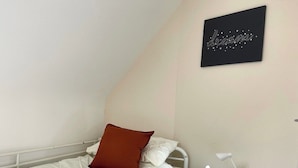 Un dormitorio con una cama, una mesita de noche, una lámpara y una obra de arte en la pared.