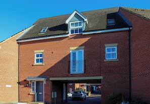 A two-story brick building with a flat roof, a central entrance, and a car parked in the driveway.