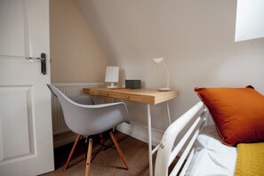 A bedroom with a bed, a desk, a chair, and a radiator.