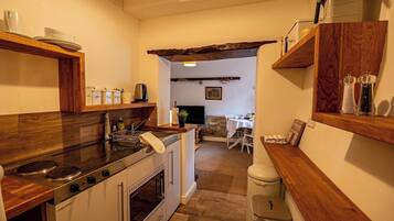 A kitchen with a stove, oven, and wooden countertops. There is a dining area with a table and chairs visible in the background.