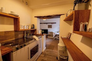 A kitchen with a stove, oven, and wooden countertops. There is a dining area with a table and chairs visible in the background.
