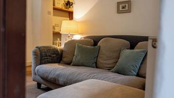 Un salon avec un canapé, une lampe et un tableau encadré au mur.
