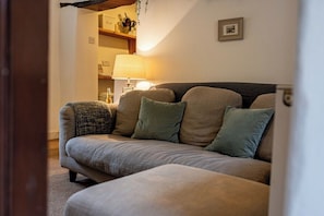 A living room with a sofa, a lamp, and a framed picture on the wall.