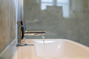 Ein Waschbecken mit einem chromfarbenen Wasserhahn und fließendem Wasser.