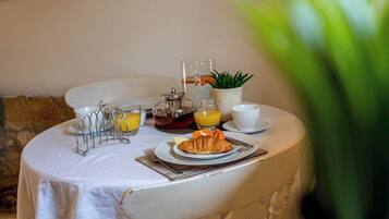 Une table de petit-déjeuner avec un croissant, du jus d’orange et une cafetière.