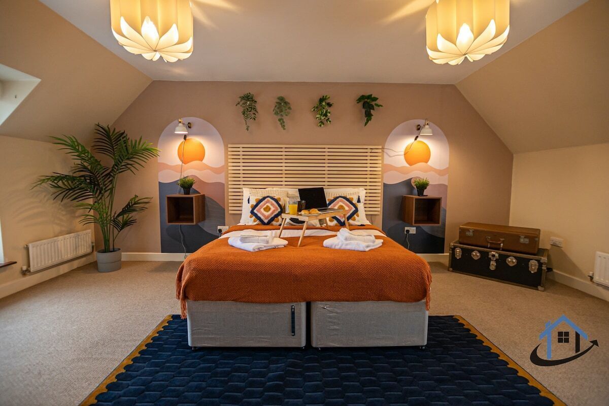 A bedroom with a bed, bedside tables, a radiator, a potted plant, and a suitcase.