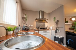A modern kitchen with a stainless steel sink, wooden countertop, and a stove. - Minchin House 3 bed parking sleeps 8 (Northamptonshire)