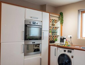 A compact kitchen with a built-in oven, microwave, and washing machine. - Minchin House 3 bed parking sleeps 8 (Northamptonshire)