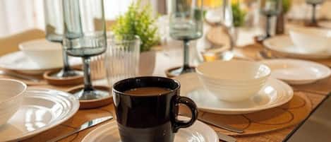 Une table à manger dressée avec des assiettes, une tasse noire et des verres transparents.