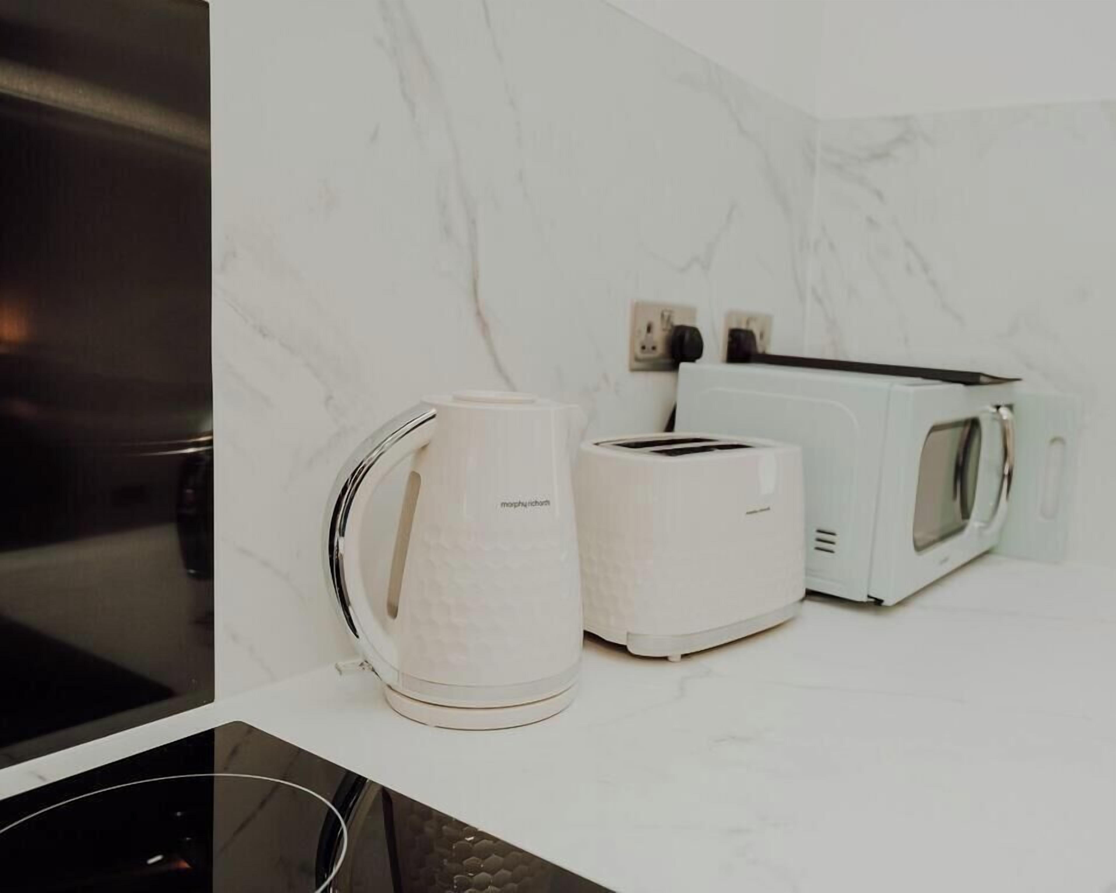 A kitchen with a white marble backsplash, a coffee maker, a toaster, and a microwave.