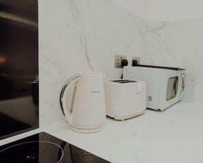 A kitchen with a white marble backsplash, a coffee maker, a toaster, and a microwave. - Apt 6 Manor House 1 Bed 1 bath sleeps 2 parking (Desborough)