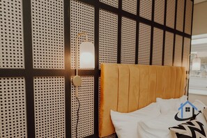 A hotel room with a bed, a wall with a perforated design, and a bedside lamp. - Apt 6 Manor House 1 Bed 1 bath sleeps 2 parking (Desborough)