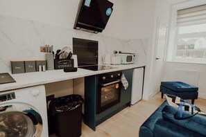 A compact kitchen with a microwave, oven, and a small countertop area. - Apt 6 Manor House 1 Bed 1 bath sleeps 2 parking (Desborough)