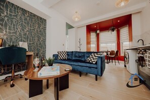 A modern living room with a blue sofa, a wooden coffee table, and a patterned wall. - Apt 6 Manor House 1 Bed 1 bath sleeps 2 parking (Desborough)