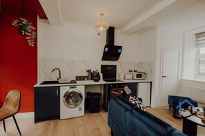 A compact kitchen with a washing machine, a microwave, and a built-in oven. - Apt 6 Manor House 1 Bed 1 bath sleeps 2 parking (Desborough)