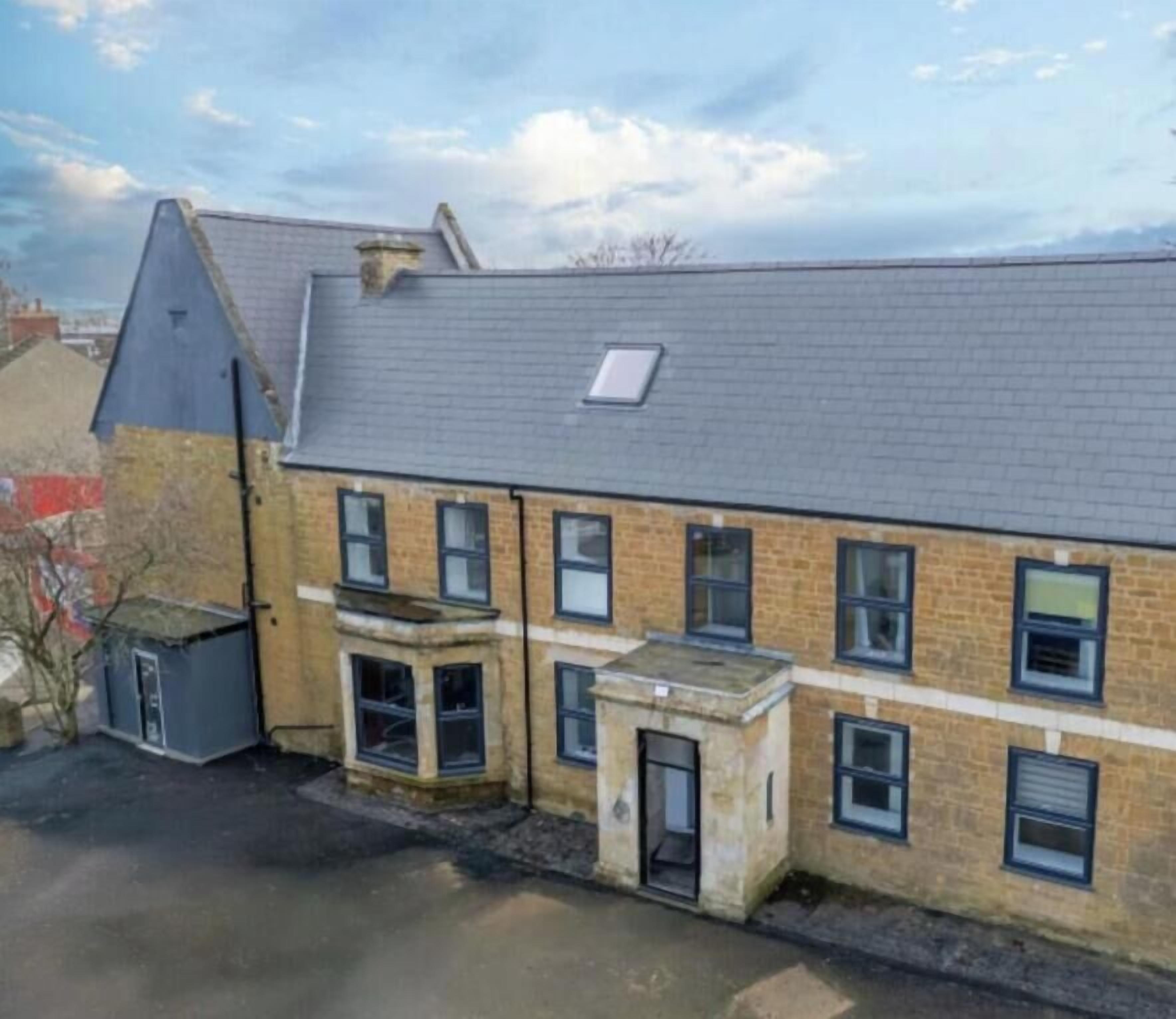Un bâtiment à deux étages, doté d’un toit en pente, de nombreuses fenêtres et d’un petit balcon.