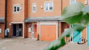 En byggnad i flera våningar, byggd av tegel, med en stor garageport i mitten och en mindre dörr på bottenvåningen.