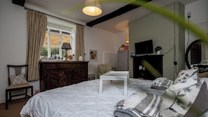 Une chambre à coucher avec un grand lit, une table de chevet, une chaise, une commode et une fenêtre avec des rideaux.
