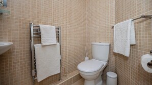 Une salle de bain équipée de toilettes, d’un porte-serviettes et d’une poubelle.
