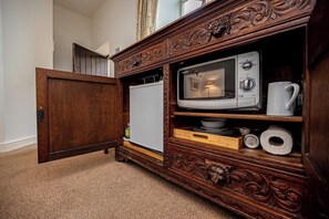 A wooden cabinet with a microwave and a coffee maker.