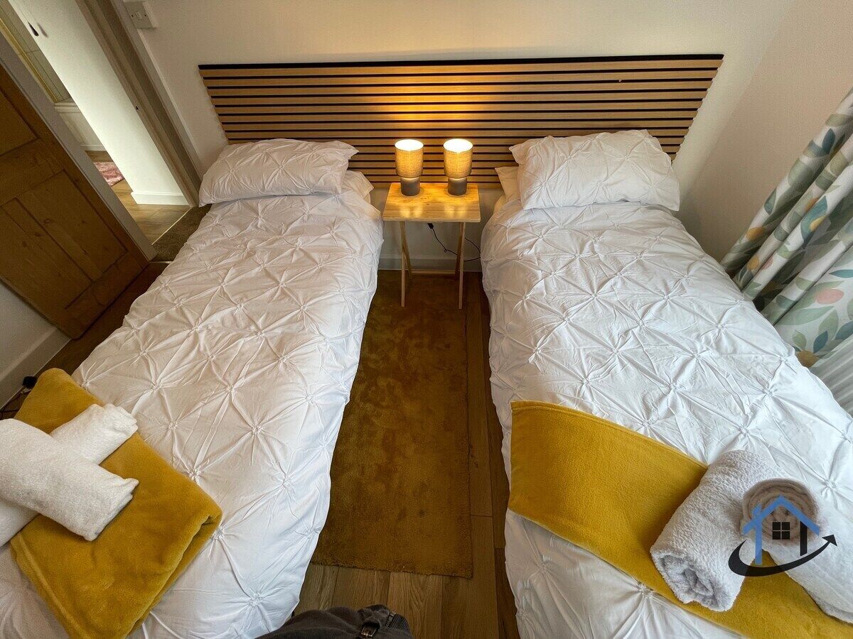 Habitación doble con dos camas, una mesita de noche y cabecero.