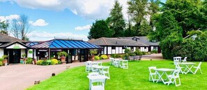Un hotel con una zona de estar al aire libre techada y un césped bien cuidado.