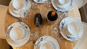 A round dining table set with white plates and blue floral patterns, accompanied by wine glasses and cutlery.
