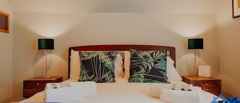 Una habitación de hotel con cama, dos mesitas de noche y dos lámparas.