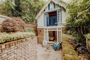 A two-story house with a balcony, a brick wall, and a garden area. - Unique Boathouse, detached free parking x4 cars (Greater London)