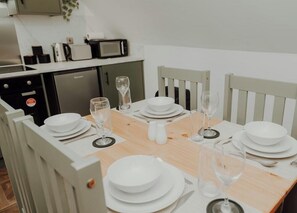 A dining table set with white plates, glasses, and cutlery, with a microwave and cabinets in the background. - Apt 5 - 3 Bed 2 bathroom sleeps 5 parking wifi (Desborough)