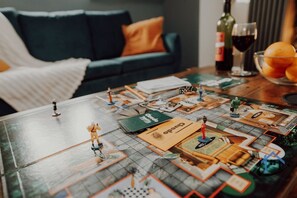 Jogo de tabuleiro montado em uma mesa, com tabuleiro, peças e cartas.