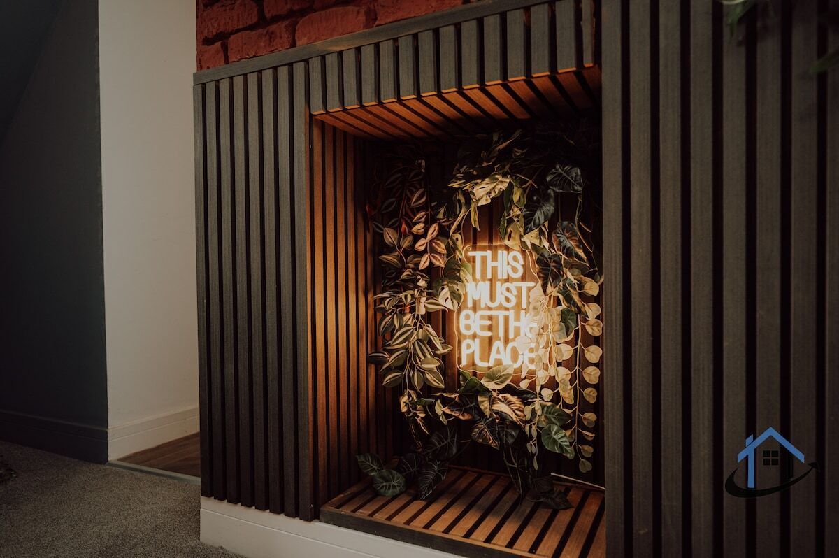 Un interior moderno con una pared de listones de madera y un letrero de neón que dice 'THIS MUST BE THE PLACE'.