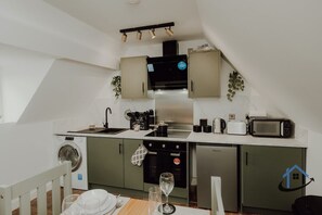 A compact kitchen with a washing machine, oven, microwave, and a dining area with a table and chairs. - Apt 5 - 3 Bed 2 bathroom sleeps 5 parking wifi (Desborough)