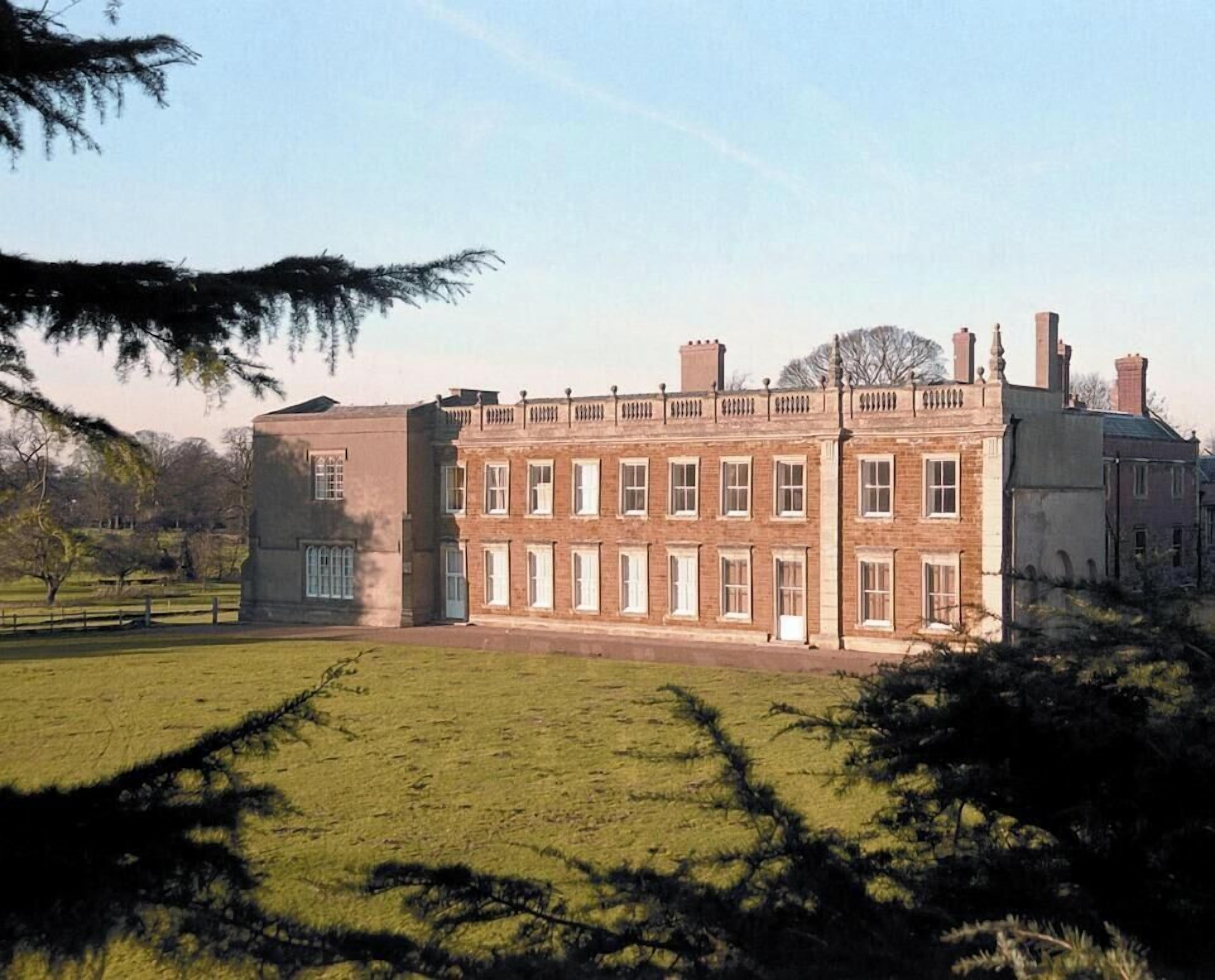 A large brick building with a symmetrical facade, multiple windows, and a central entrance.
