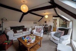 Un salon chaleureux de style industriel, avec des meubles blancs, une table basse en bois et un coin repas comprenant une table et des chaises.