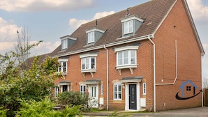 A two-story brick house with a pitched roof, multiple windows, and a front door. - Bluebell House, sleeps 7, parking x2, garden (Corby)