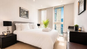 A modern hotel room with a large bed, bedside tables, a desk, and a view of the city. - Luxury City View AC Balcony Rooftop Panoramic - Fast Wi-fi, near Sky Garden (London)