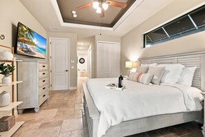 Een slaapkamer met een bed, een plafondventilator, een televisie en uitzicht op het landschap.