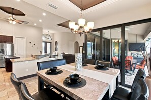A modern dining area with a large table, chairs, and a chandelier. - Dog-Friendly Canalfront Retreat with Heated Pool & Kayaks (Cape Coral)