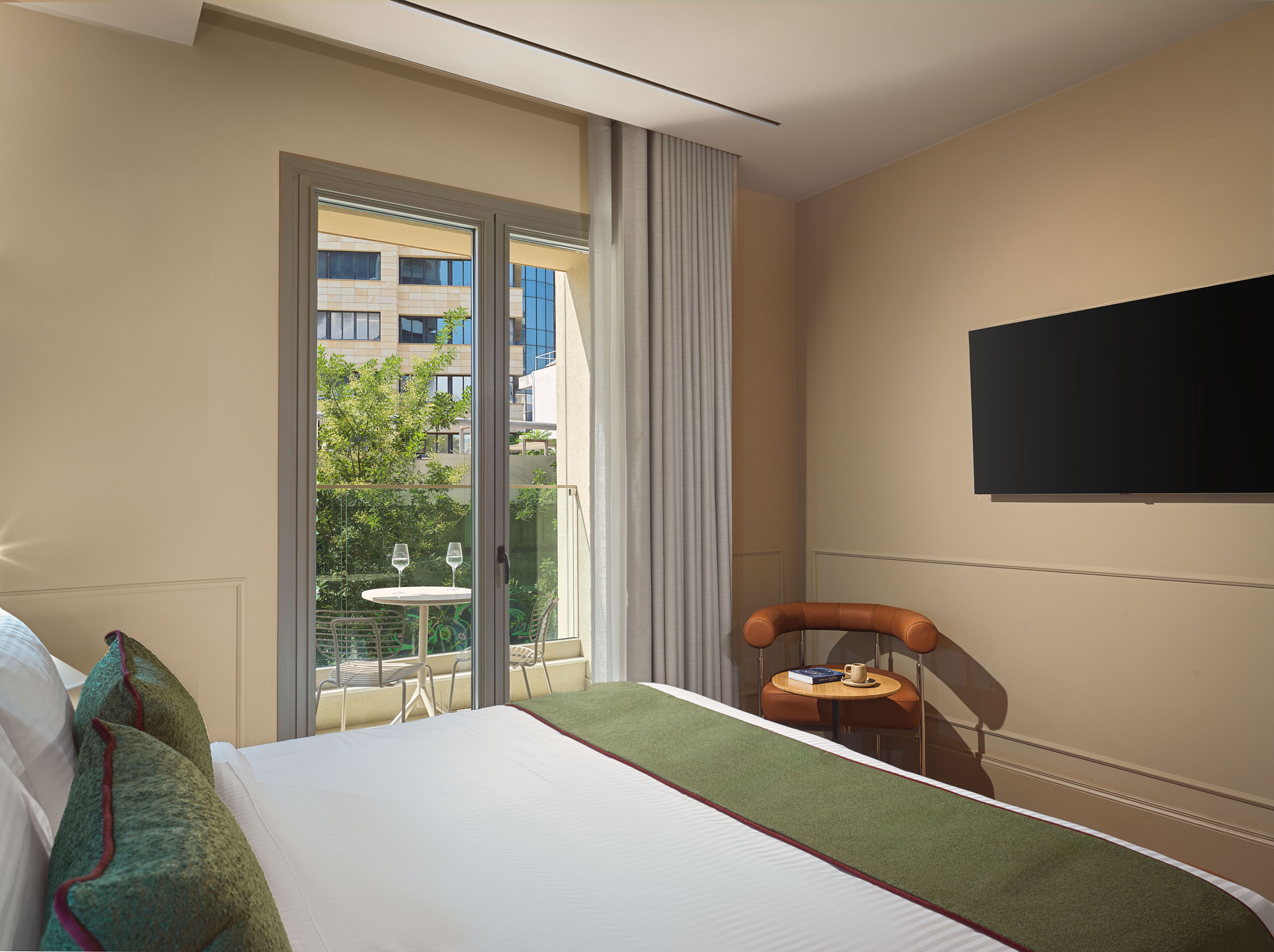 Une chambre d’hôtel avec un lit, une petite table avec une tasse, une chaise et une vue sur l’extérieur.