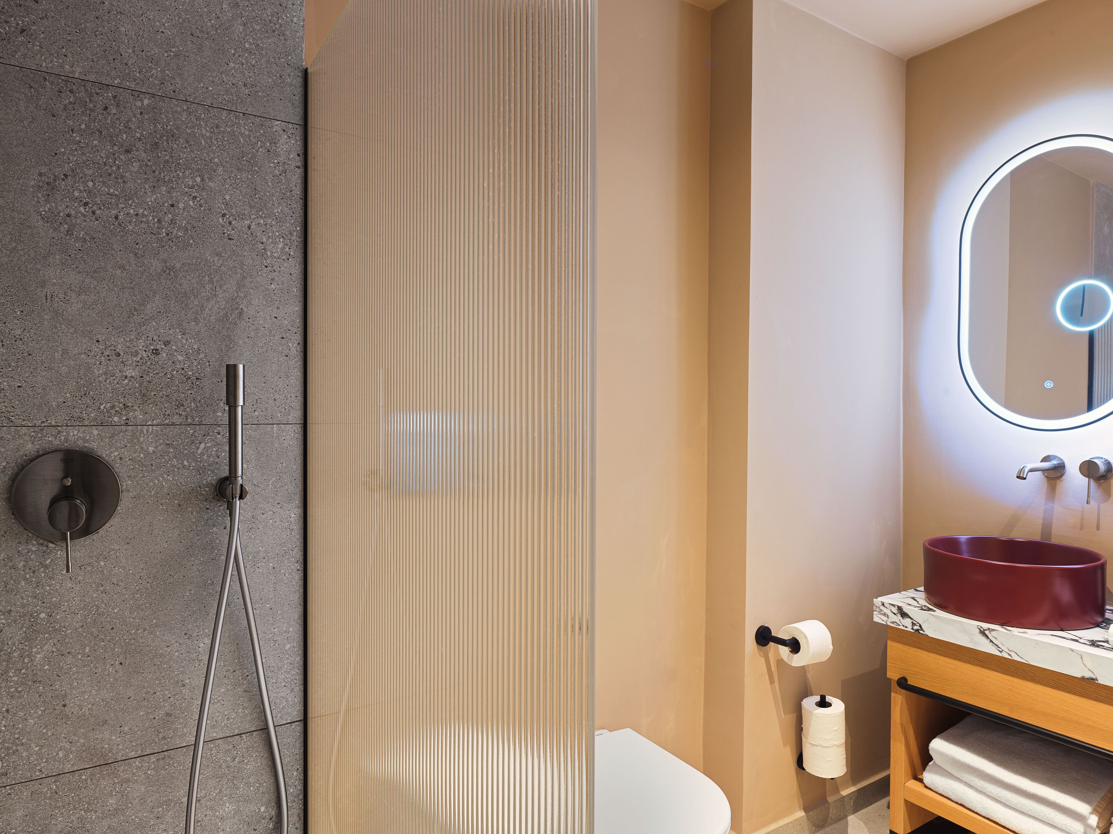 A bathroom with a shower, toilet, and sink with a marble countertop.