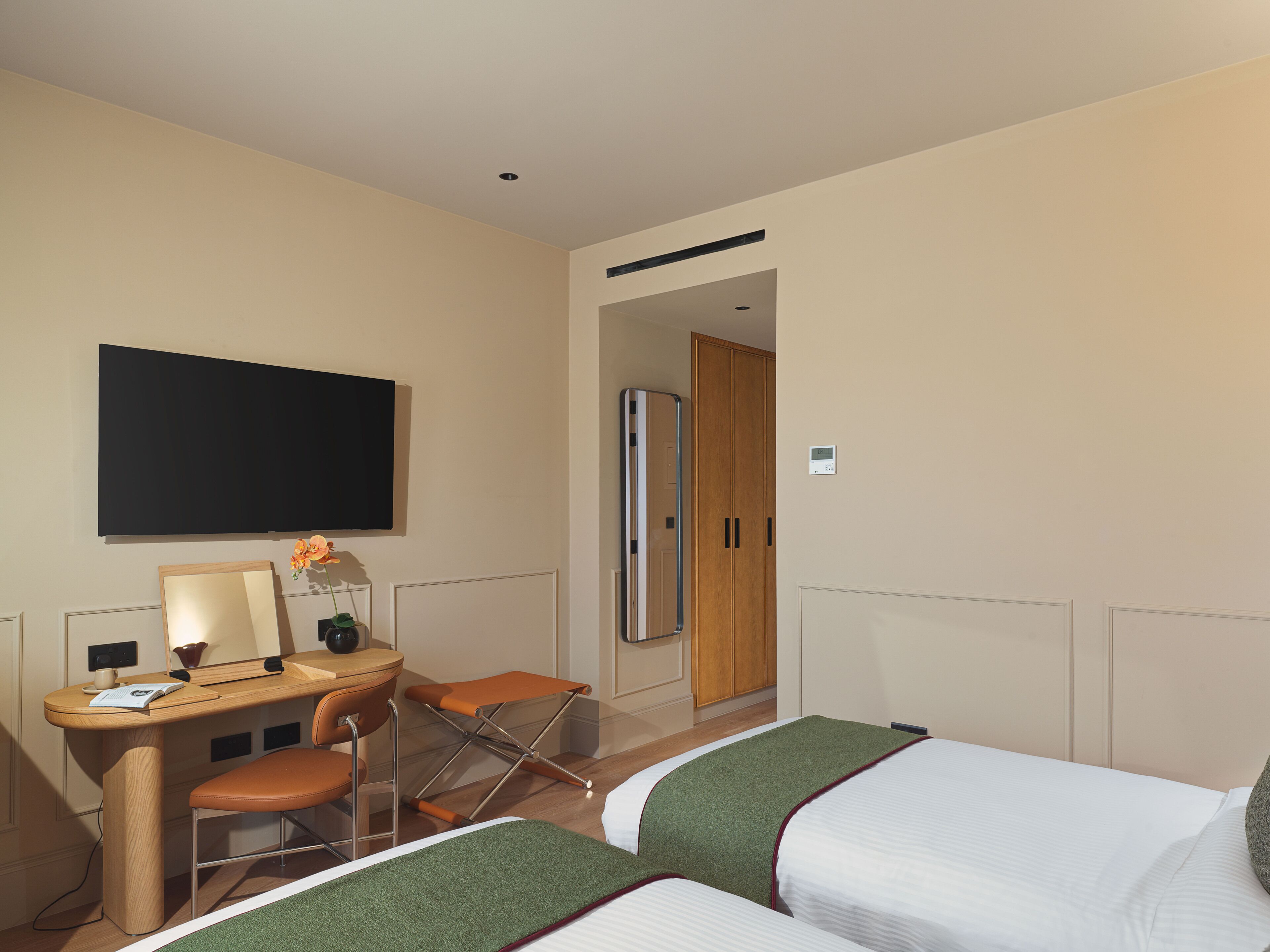 Una habitación de hotel con escritorio, dos sillas, cama, televisor y armario.