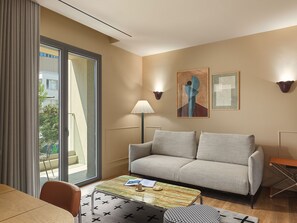 A modern hotel room with a sofa, a coffee table, a lamp, and artwork on the walls. - Leonardo Boutique Hotel Venetian Nicosia (Nicosia)