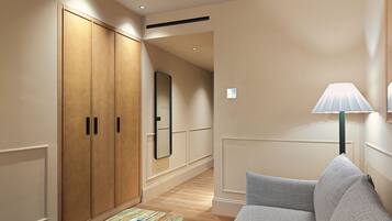 Une chambre d’hôtel avec une armoire en bois, un miroir, un canapé et une table sur laquelle se trouvent un magazine et une tasse.